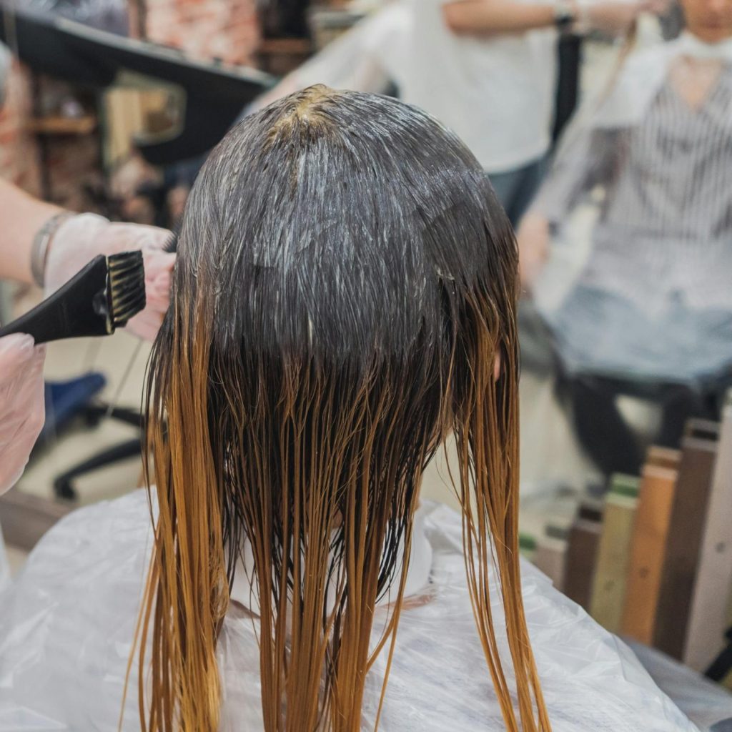 Hair coloring process in a salon, showcasing stylist applying color to client's hair.