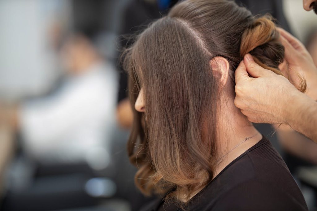 Close-up of a hairstylist creating an elegant hairstyle for a woman in a salon.